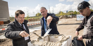 Drei Leute auf einer Baustelle spachteln was zusammen