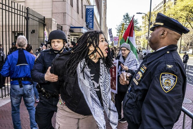 Eine Frau mit Palestinensertuch rangelt mit einem Polizisten