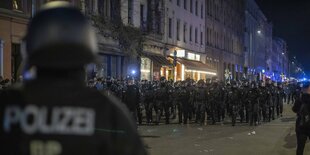 Eine große Gruppe Polizist:innen in Helmen und Riotgear läuft am Abend des 1. Mais 2023 durch Kreuzberg.