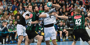 Harald Reinkind vom THW Kiel hat den Ball und ist umringt von Hannovers Spielern Ilija Brozovic und Martin Hanne.