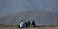 Vier afghanische Frauen sitzen an einem Straßenrand und gucken auf Berge