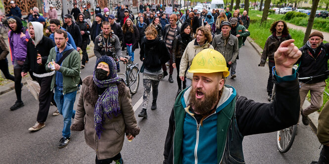 Mann mit Bauhelm und andere Menschen auf einer Straßendemo