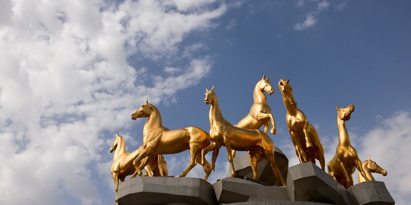 Goldene Pferdestatuen vor blauem Wolkenhimmel