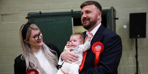 Politiker mit Ehefrau und Kind vor der Presse.