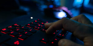 Ein Mensch tippt auf einer Tastatur im Dunkeln