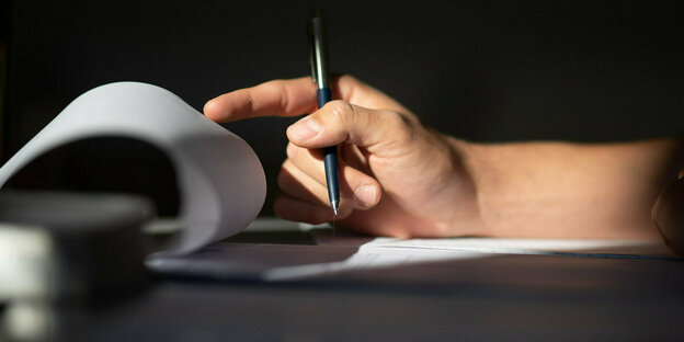 Eine Hand und ein Stift mit Papier.