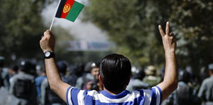 Ein Mann mit afghanischer Fahne bei einer Demonstration