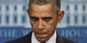 Barack Obama schaut nach unten, die Lippen aufeinandergepresst.