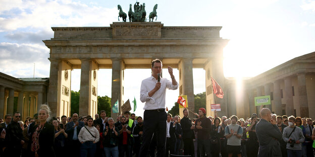 Ein Mann spricht während einer Demonstration vor dem Brandenburger Tor zu den Protestierenden.