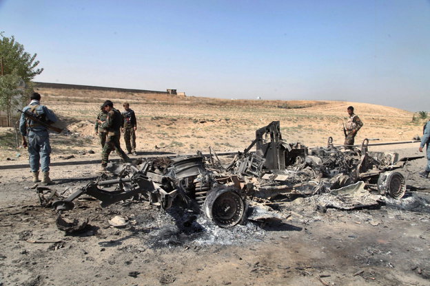 Soldaten stehen neben einem abebrannten Auto