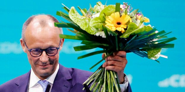 Friedrich Merz, CDU-Bundesvorsitzender, hält seinen Blumenstrauss nach der Wahl zum Bundesvorsitzenden beim CDU-Bundesparteitag hoch.