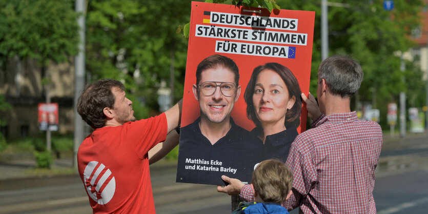 Freiwillige hängen Wahlplakate auf.