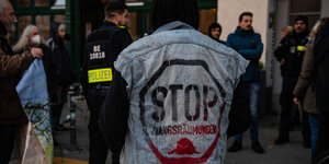 Ein Mann steht mit dem Rücken zur Kamera, auf seiner Jeansjacke steht "Stop Zwangsräumungen"