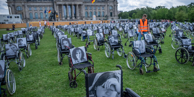 Rollstühle mit Bildern und Namen von Long Covid, ME/CFS und Post Vac- Betroffenen stehen vor dem Reichstagsgebäude in Berlin.