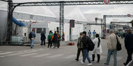 Menschen laufen in Richtung der Leichtbauhallen, die in Tegel als Massenunterkunft für Flüchtlinge dienen