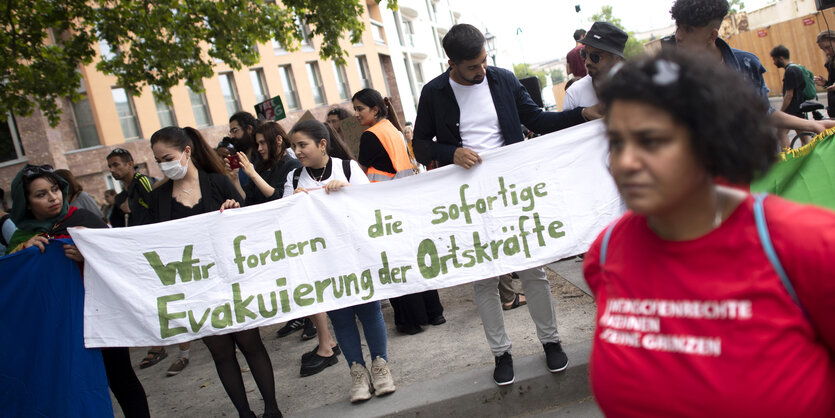 Demonstranten mit Plakat Wir fordern die sofortige Evakuierung der Ortskraefte und Solidaritaet mit Afghanistan bei der Kundgebung und Demonstation vom Fluechtlingsrat Berlin