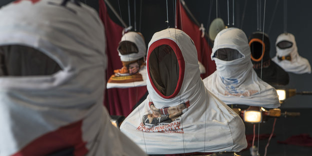 Maskierte Oberkörper sind in der Ausstellung installiert.