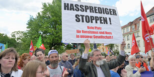 Ein Demonstrant unter vielen hält ein Plakat gegen Gewalt an Politikern hoch