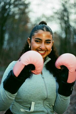 Porträt von Fatima, sie trägt rosa Boxhandschuhe und lacht in die Kamera