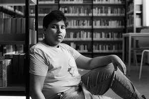 Maaradji sitzt mit einem sehr ernsten Gesichtsausdruck in einer Bibliothek. Foto in schwarz weiss