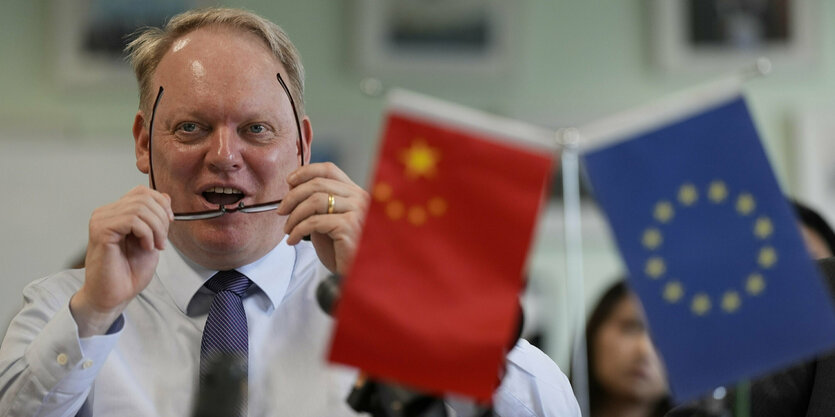 Der Präsident der Handelskammer der Europäischen Union in China, Jens Eskelund, spricht während einer Pressekonferenz der Europäischen Kammer in Peking. Rechts im Bild sind eine chinesische und eine EU-Flagge zu sehen.