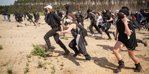 Schwarz gekleidetet Demonstrantinnen rennen durch den Sand