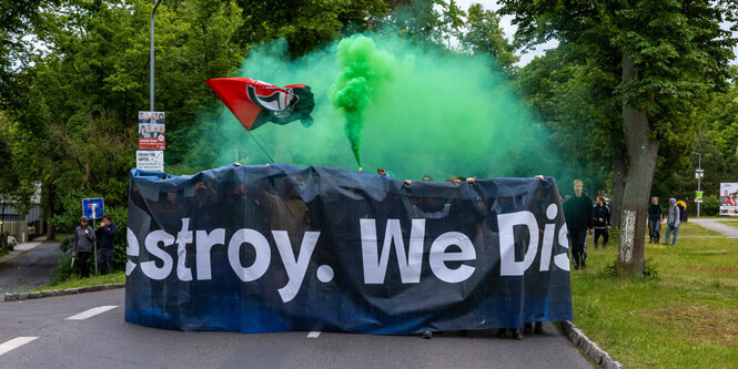 Protestierende hinter Banner mit Antifa-Fahne, grüner Rauch steigt auf