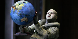 Ein Operschauspieler hält einen Globus in der Hand