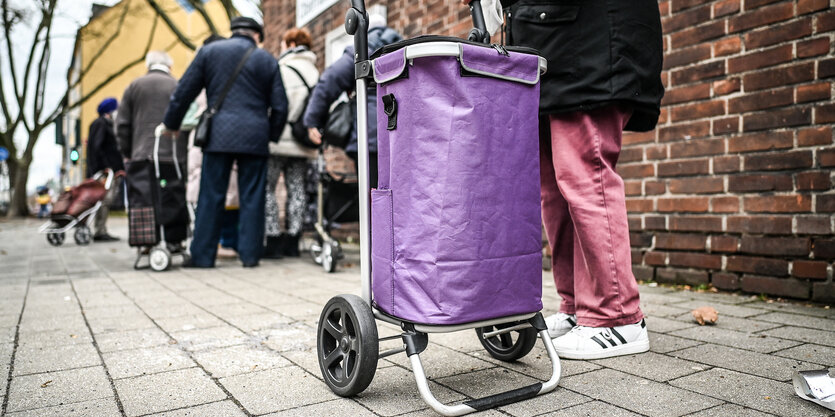 Menschen stehen auf dem Gehweg in einer Warteschlange