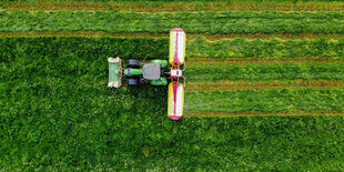 Ein Landwirt mäht mit seinem Traktor eine Wiese