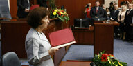Gordana Siljanovska Davkova steht vor einem Tisch mit einer roten Mappe in der Hand im Parlament