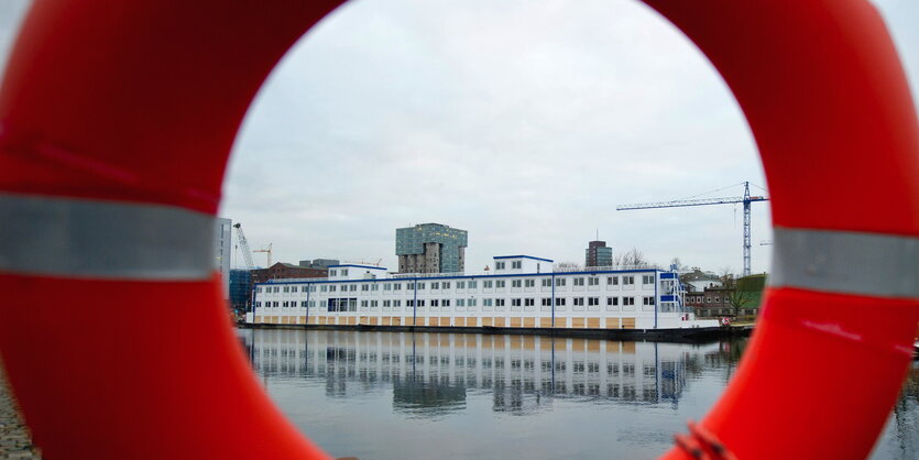 Durch einen Rettungsring ist eine Wohnschiff für Geflüchtete zu sehen