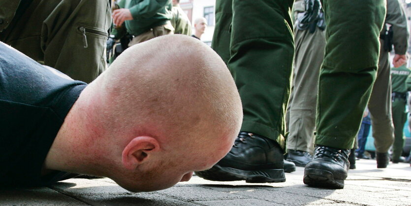 Ein Rechtsextremer liegt vor Polizisten auf dem Boden