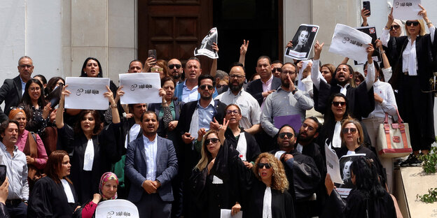 Demonstranten stehen mit Schildern in der Hand auf den Stufen des Justizpalastes in Tunis.