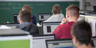 Schülerinnen und Schüler sitzen hinter Laptops in einem Klassenzimmer.