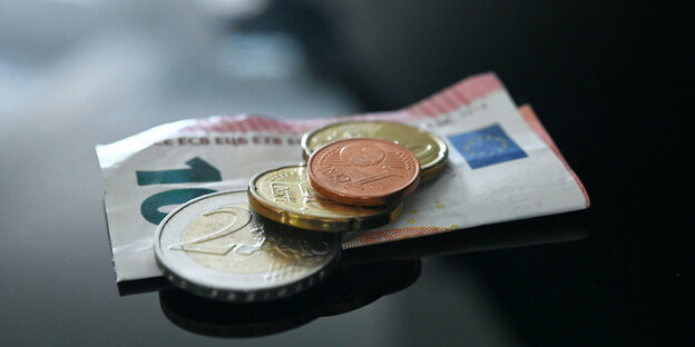 Münzen und ein Geldschein im Wert von 12,41 Euro liegen auf einer schwarzen Fläche