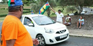 Ein Demonstrant schwenkt eine Fahne der sozialistischen Nationalen Befreiungsfront der Kanaken an einem Fahrzeugkontrollpunkt in Noumea