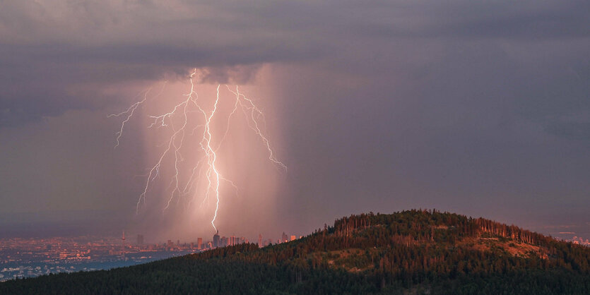 Ein Blitz schlägt vom Großen Feldberg im Taunus aus gesehen im Rhein-Main-Gebiet über der Frankfurter Skyline ein