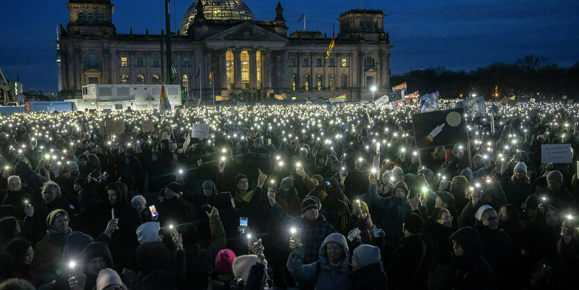 Demonstrierende im Dunkeln, die Handytaschenlampen und Schilder hochhalten