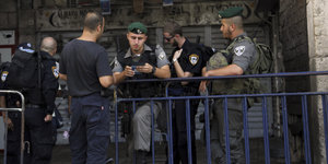 Soldaten hinter einem Gitter kontrollieren einen Palästinenser