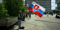 Ein Mann hält die slowakische Fahne in der Hand