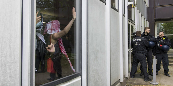 Proteste in einem Gebäude, davor Polizei.