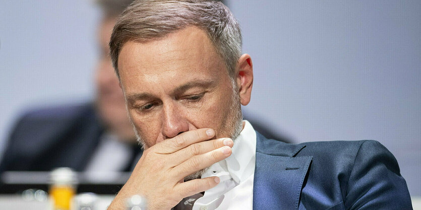 Christian Lindner, Bundesvorsitzender der FDP und Bundesminister der Finanzen, hält sich nachdenklich eine Hand vor den Mund.