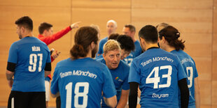 Fußballteam mit blauen Trikots in der Halle beim Gespräch