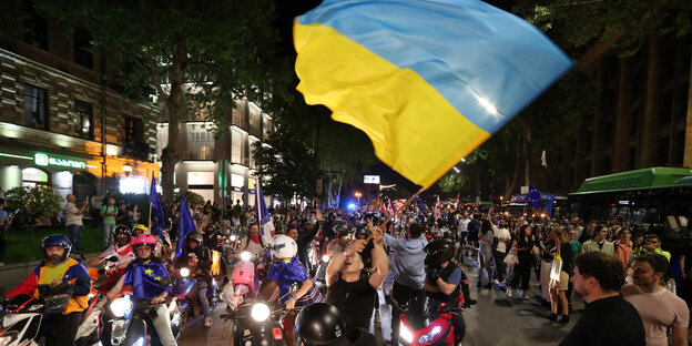 Ein Demonstrant schwenkt in Georgiens Hauptstadt die ukrainische Flagge