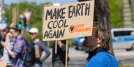 Ein Klimaaktivist steht mit einem Schild mit der Aufschrift "Make earth cool again"
