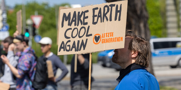 Ein Klimaaktivist steht mit einem Schild mit der Aufschrift „ 