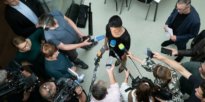 Aus der Vogelperspektive: Sahra Wagenknecht umringt von Journalist*innen, die ihr Aufnahmegeräte und Mikros entgegenhalten