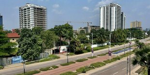 Blick auf die Hauptstadt der Demokratischen Republik Kongo Kinshsa, zu sehen ist eine Straße, Hochhäuser und Bäume