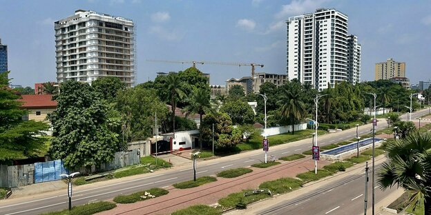 Blick auf die Hauptstadt der Demokratischen Republik Kongo, Kinshsa, mit einer Straße, Hochhäusern und Bäumen